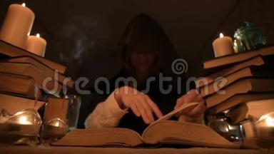 中等特写的女孩魔术师在一个黑暗的房间在烛光和寻找一个法术翻书。 低